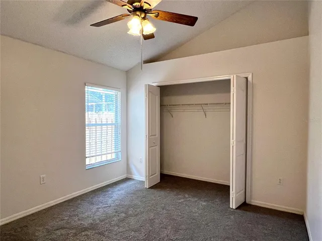 an empty room with closet and a ceiling fan
