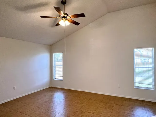 an empty room with wooden floor chandelier fan and windows