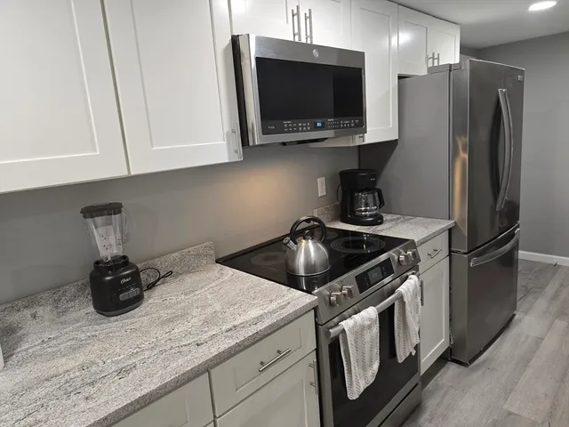 a kitchen with stainless steel appliances granite countertop a stove a refrigerator and a microwave