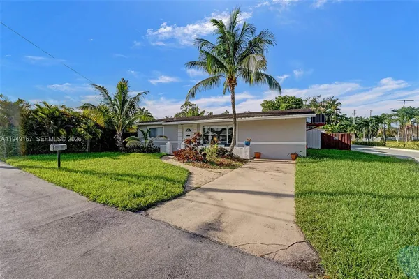 a palm tree sitting in front of a house with a big yard