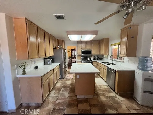 a view of kitchen with stainless steel appliances kitchen island granite countertop a sink and cabinets
