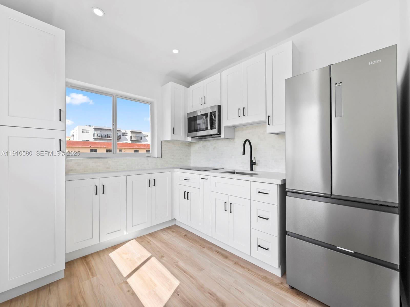 300 Northwest 7th Avenue, Unit 1 Miami, FL 33128 - Photo 3 of 10 a kitchen with stainless steel appliances a refrigerator sink and cabinets
