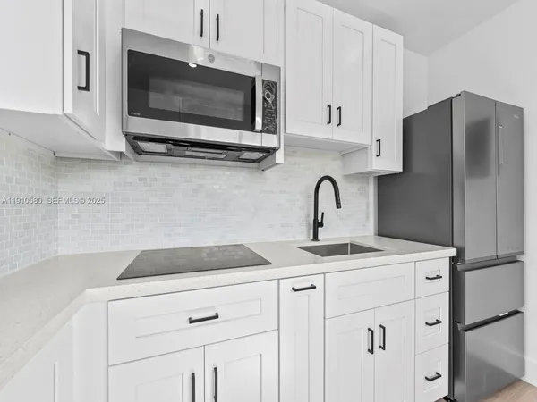 a kitchen with stainless steel appliances white cabinets a sink and a microwave