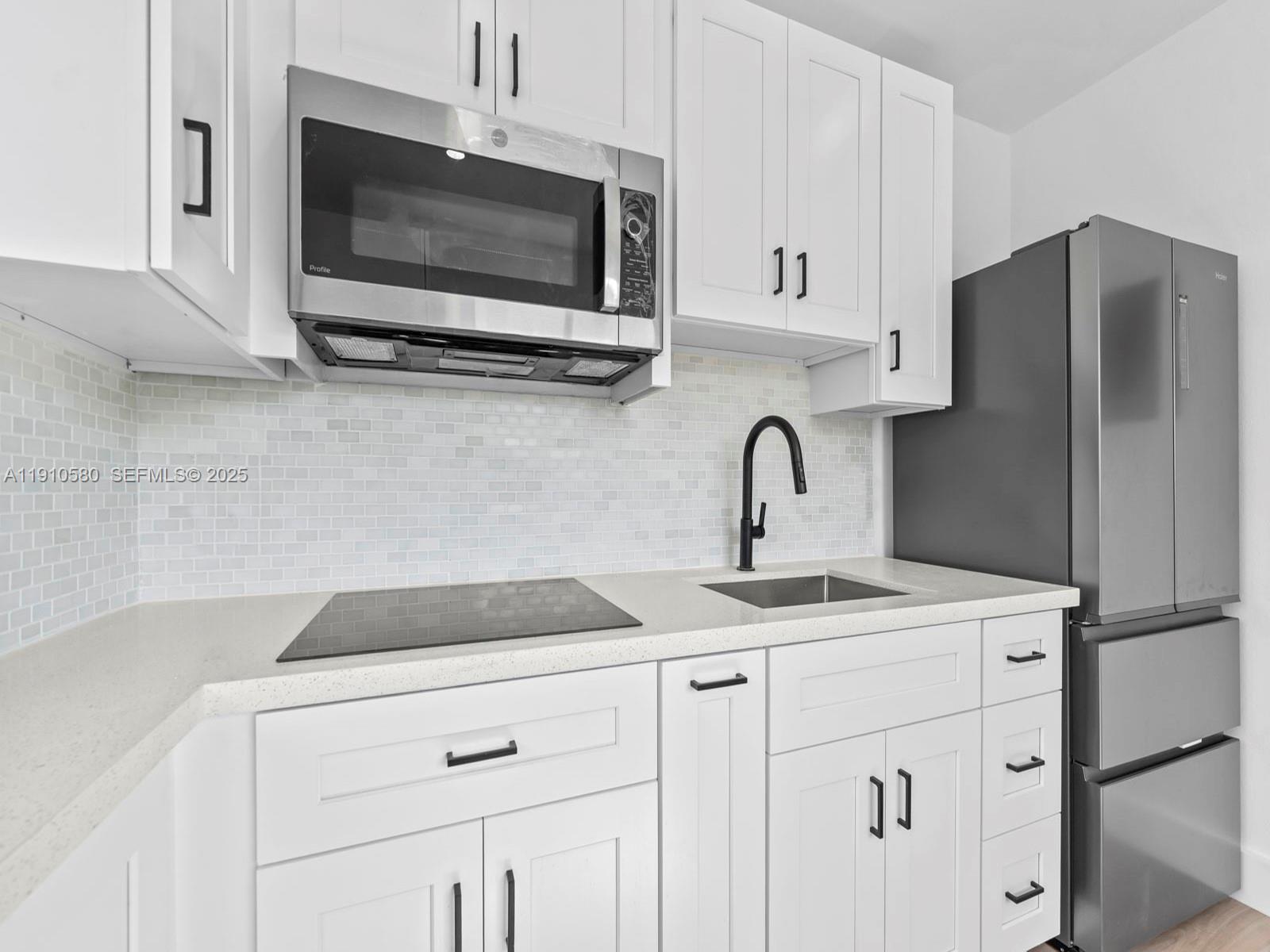 300 Northwest 7th Avenue, Unit 1 Miami, FL 33128 - Photo 4 of 10 a kitchen with stainless steel appliances white cabinets a sink and a microwave