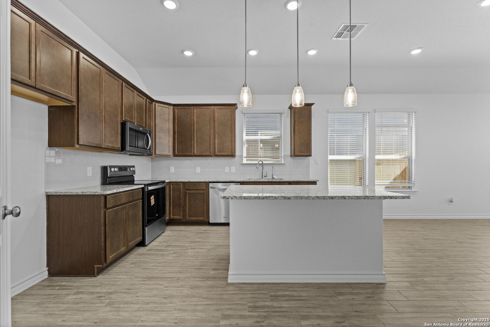 4040 Paddock Trail Seguin, TX 78155 - Photo 11 of 26 a kitchen with stainless steel appliances granite countertop wooden cabinets a sink a stove a kitchen island and a wooden floors