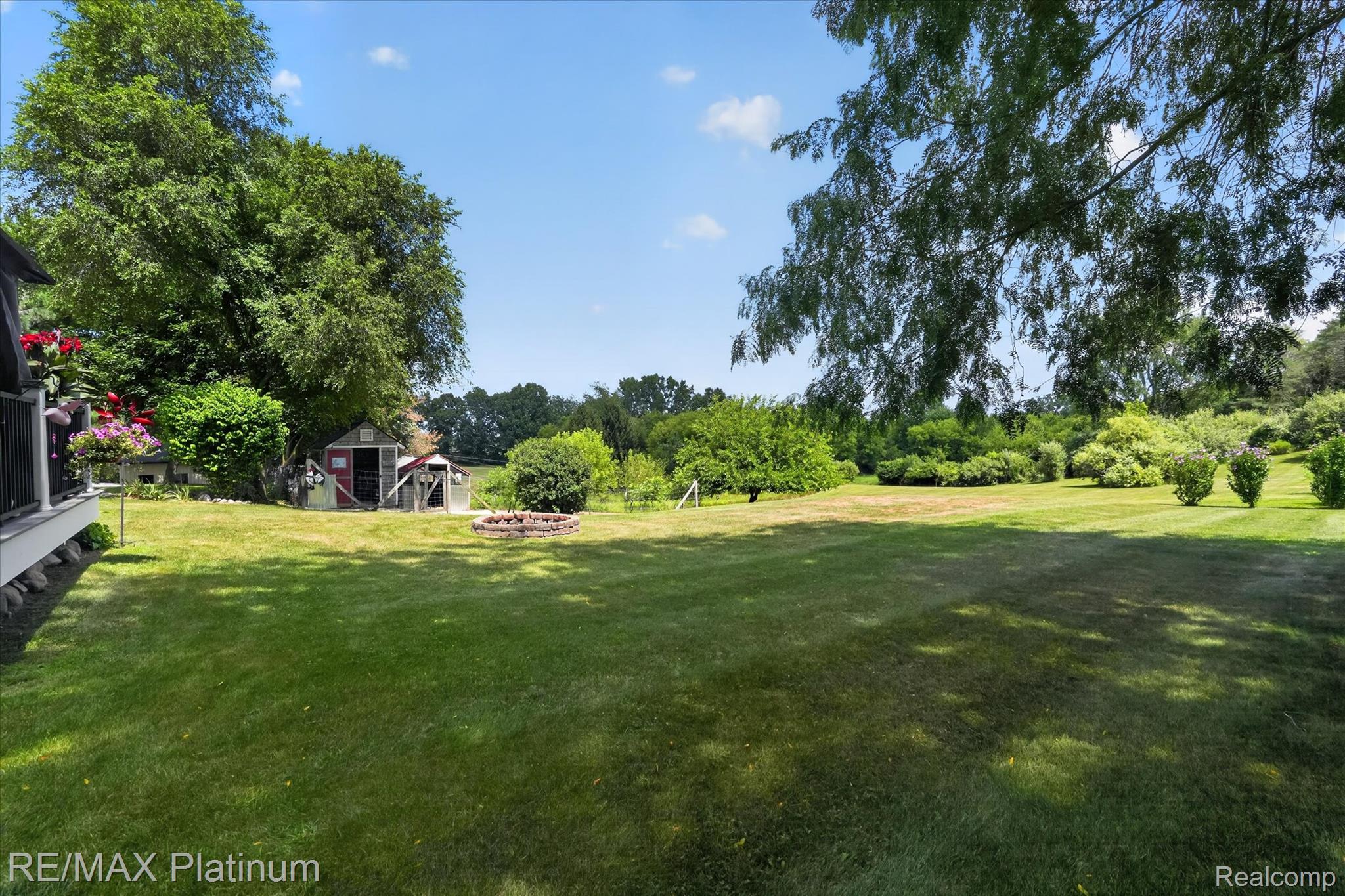 4457 Bradley Road Gregory, MI 48137 - Photo 41 of 79 Expansive lawn featuring mature trees and a dedicated fire pit area