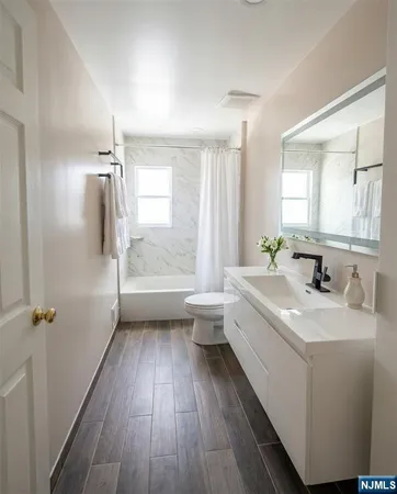 a bathroom with a sink a toilet a mirror and shower