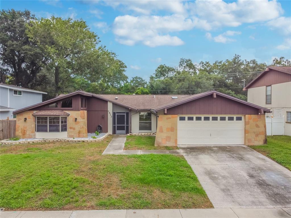 a view of house with a big yard potted plants and large tree