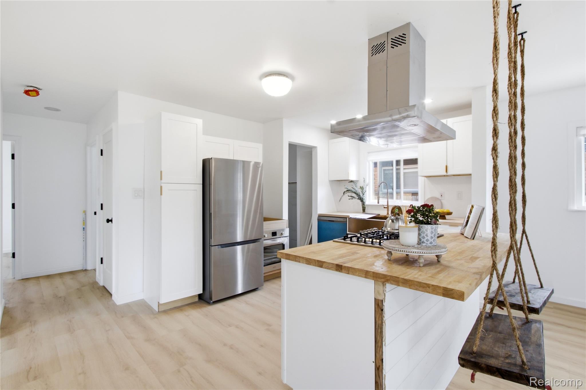 17544 Evergreen Road Detroit, MI 48219 - Photo 9 of 16 Modern kitchen featuring stainless steel appliances, a range hood, and a light-toned wood-finish island countertop