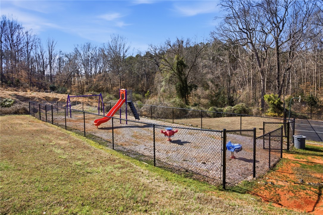 108 Hodge Street Abbeville, SC 29620 - Photo 29 of 39 A private playground, securely fenced, offers recreational enjoyment amidst natural landscaping.