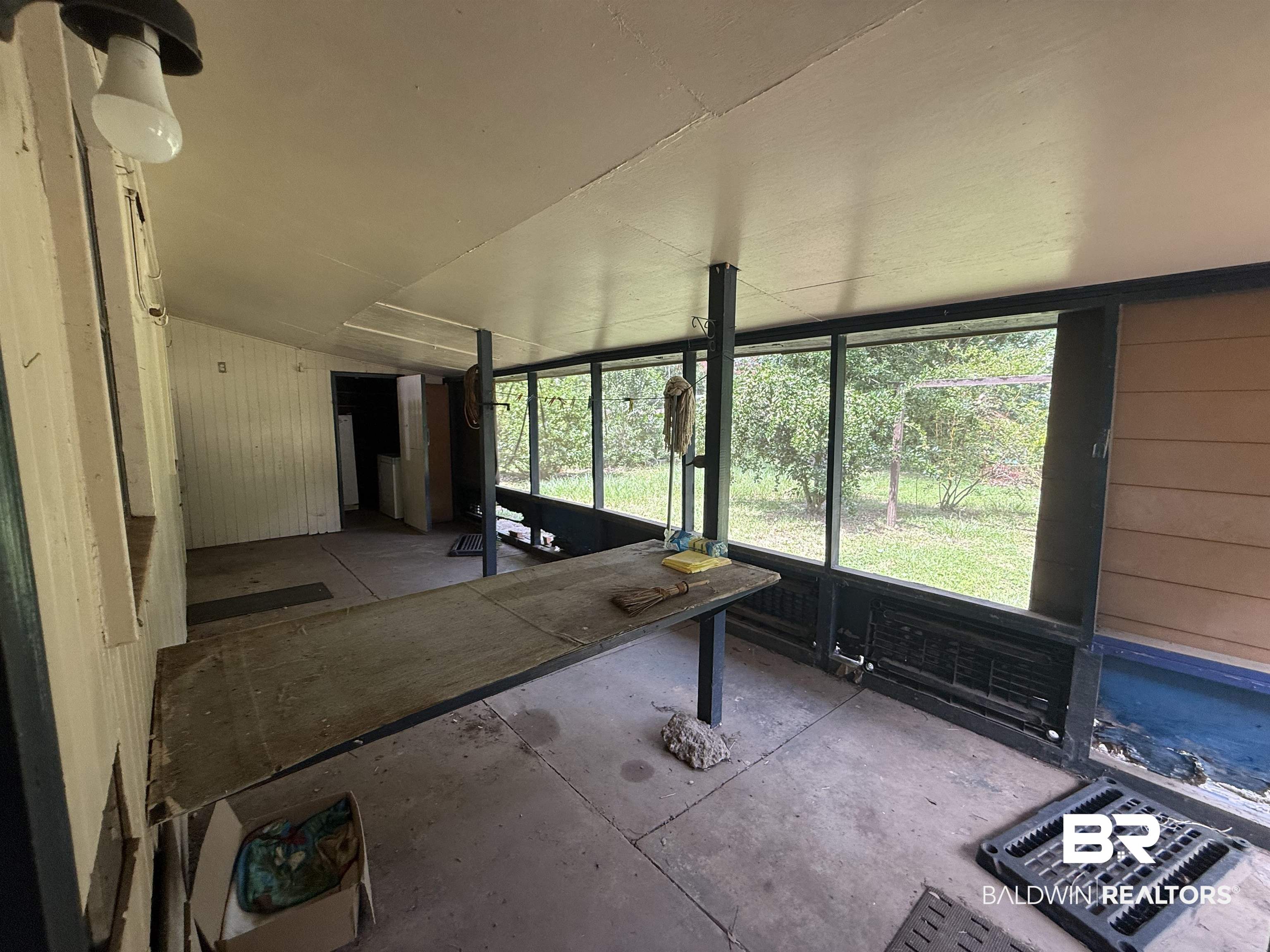 711 Wilshire Road Mobile, AL 36609 - Photo 6 of 11 Enclosed patio area with concrete flooring, screened windows, and a built-in counter