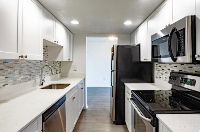 a kitchen with stainless steel appliances kitchen island granite countertop a sink stove and refrigerator