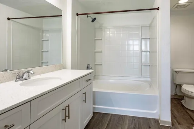 a bathroom with a granite countertop sink a toilet and shower