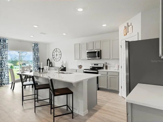 a kitchen with stainless steel appliances a table chairs refrigerator and microwave