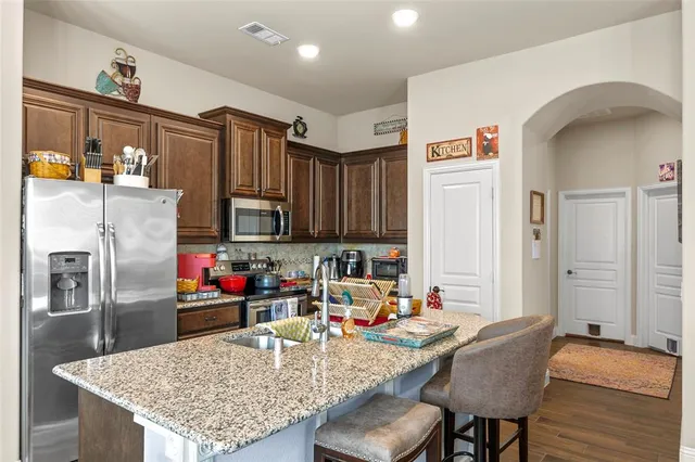 a kitchen with stainless steel appliances granite countertop a sink refrigerator and microwave