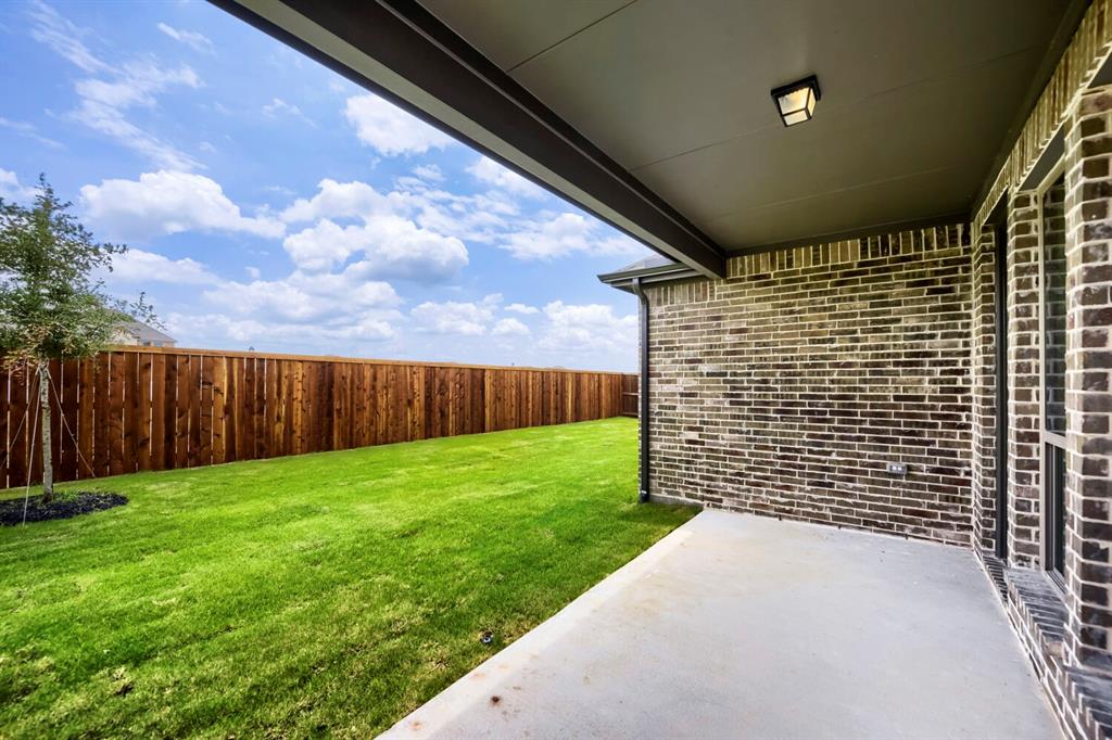 11548 Wulstone Road Haslet, TX 76052 - Photo 25 of 26 Expansive backyard featuring a manicured lawn, a full wood privacy fence, and a young tree