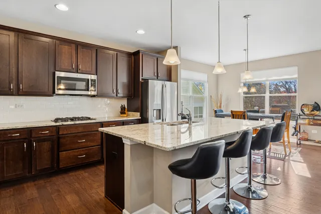 a kitchen with stainless steel appliances kitchen island granite countertop a sink a stove a refrigerator and cabinets