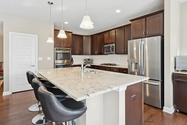 a kitchen with stainless steel appliances granite countertop a table chairs stove and refrigerator
