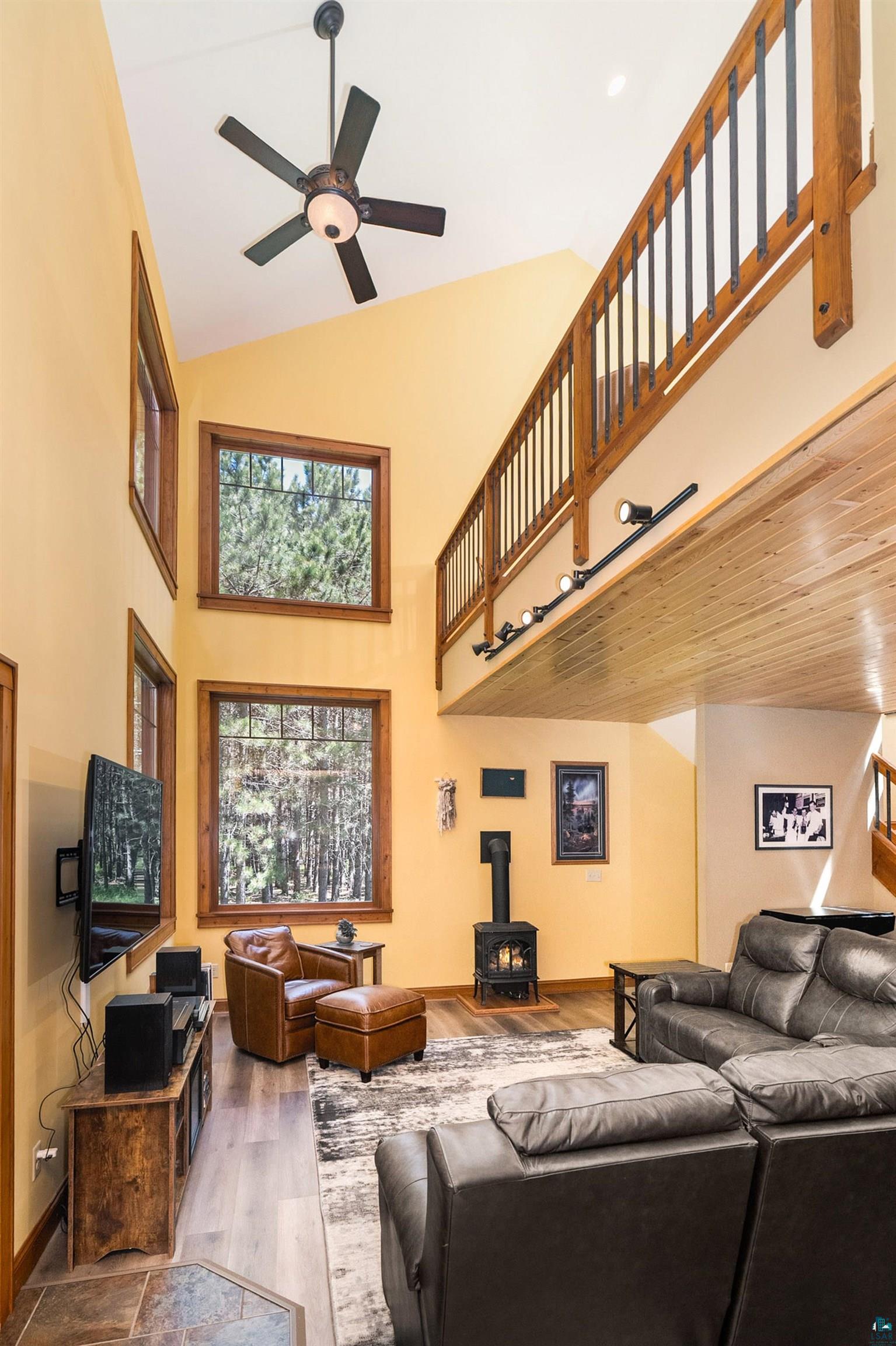 75 East Stark Road Esko, MN 55733 - Photo 16 of 87 Great room featuring a vaulted ceiling with a ceiling fan, multiple large windows, and a wood stove