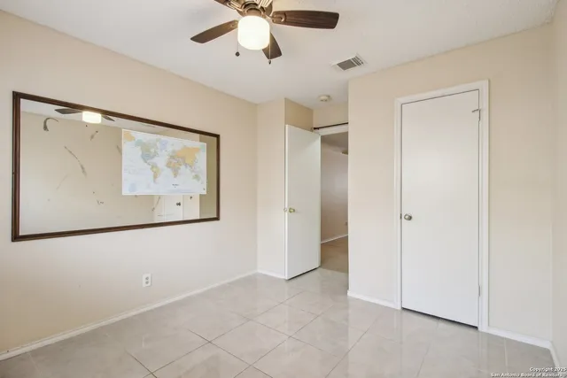 an empty room with windows and fan