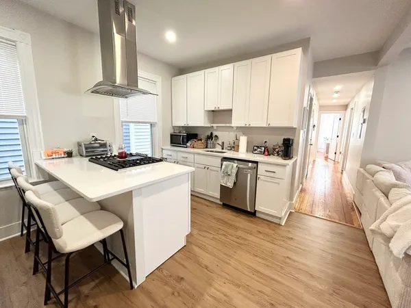 a kitchen with a stove a sink dishwasher a refrigerator and cabinets with wooden floor