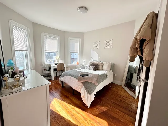 a bedroom with a bed wooden floor and window