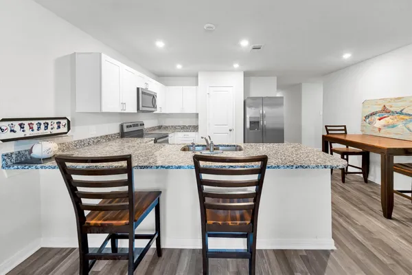 a living room with stainless steel appliances furniture and a flat screen tv