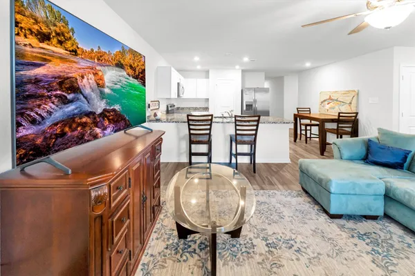 a kitchen with stainless steel appliances granite countertop a sink dishwasher stove and white cabinets with wooden floor