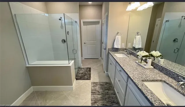 a bathroom with a granite countertop sink and mirror with bathtub