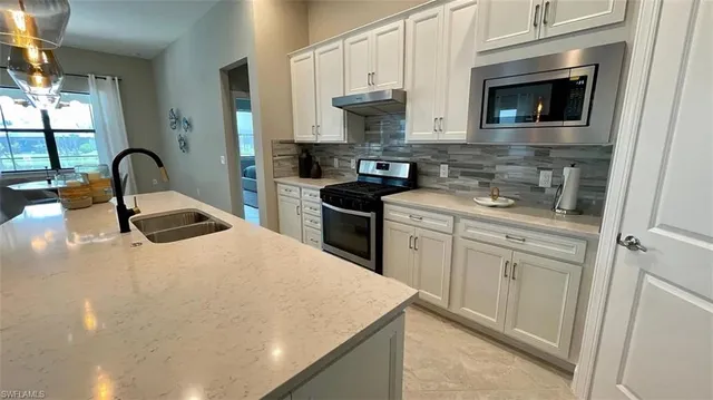 a kitchen with white cabinets and appliances