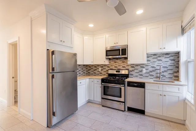 a kitchen with white cabinets and stainless steel appliances