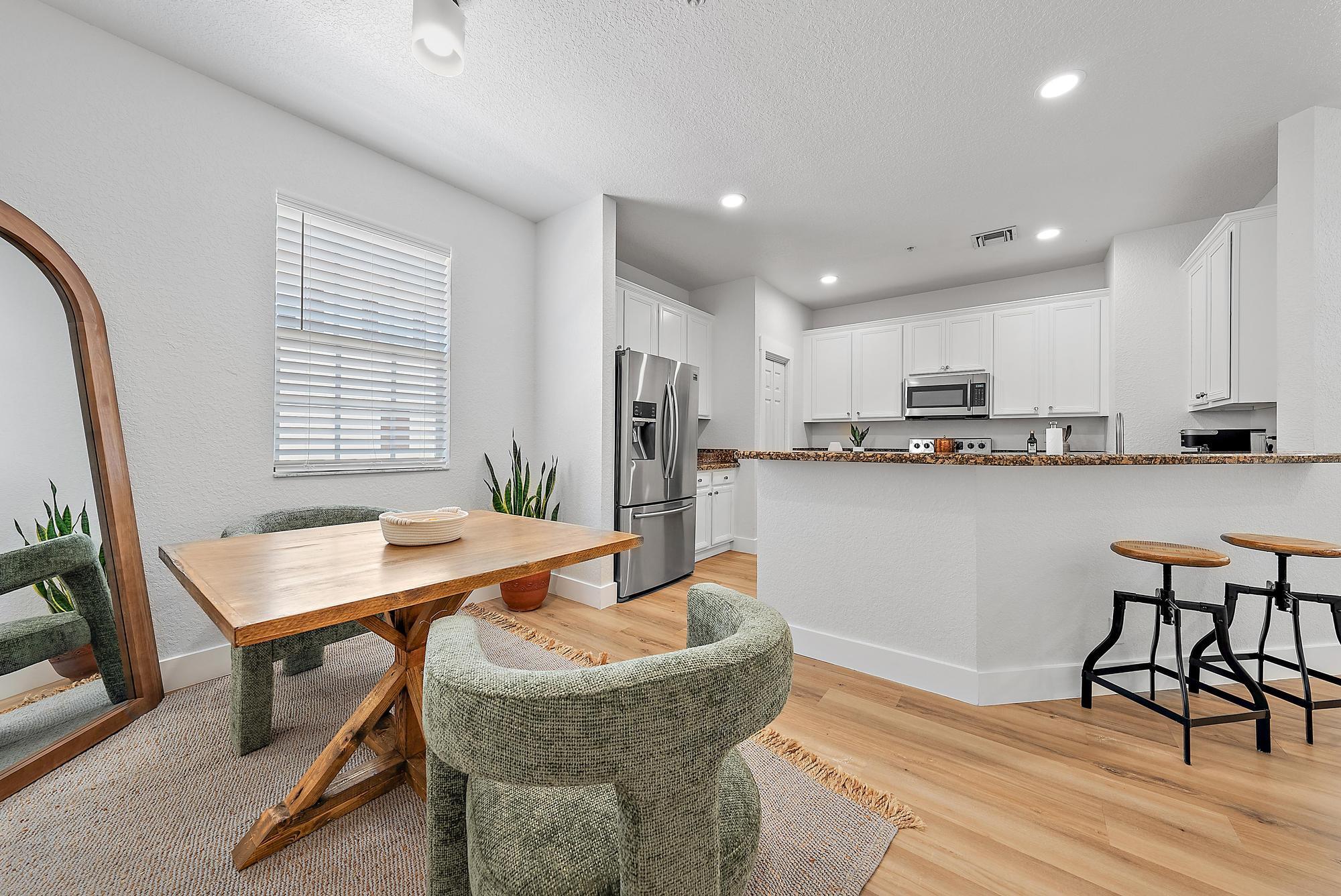 107 Pond Apple Lane, Unit 105 Jupiter, FL 33458 - Photo 12 of 37 a kitchen with stainless steel appliances granite countertop a table chairs sink refrigerator and microwave