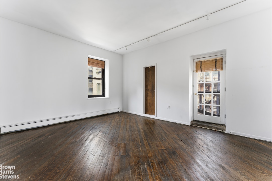 454 West 46th Street, Unit 4CS Manhattan, NY 10036 - Photo 10 of 18 an empty room with wooden floor and windows