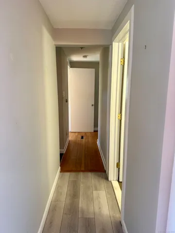 a view of a hallway with wooden floor and a bathroom