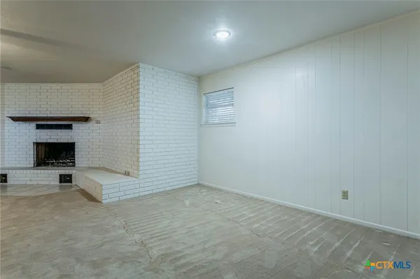 an empty room with a fireplace and cabinet