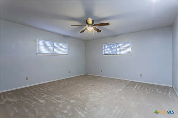 an empty room with windows and fan