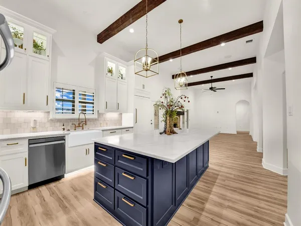 a large white kitchen with a sink dishwasher a stove and a refrigerator with wooden floor