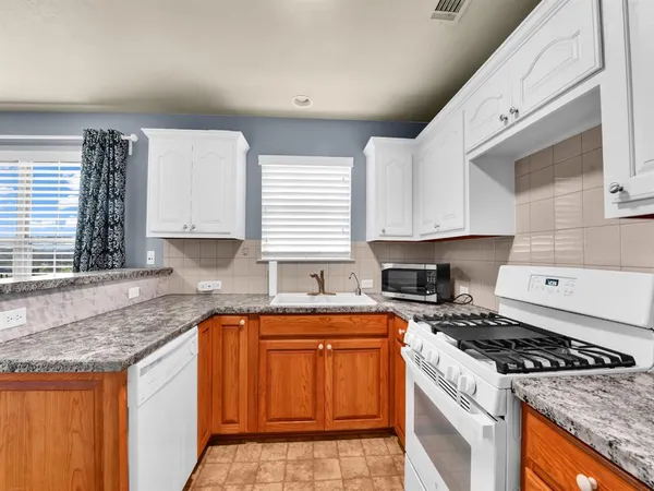 a kitchen with granite countertop a sink a stove and cabinets