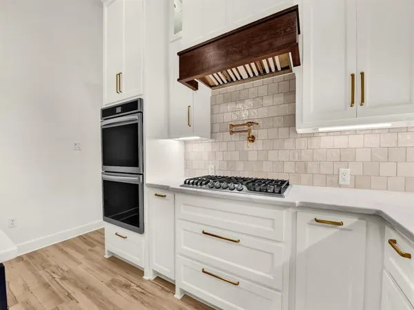 a kitchen with white cabinets and appliances