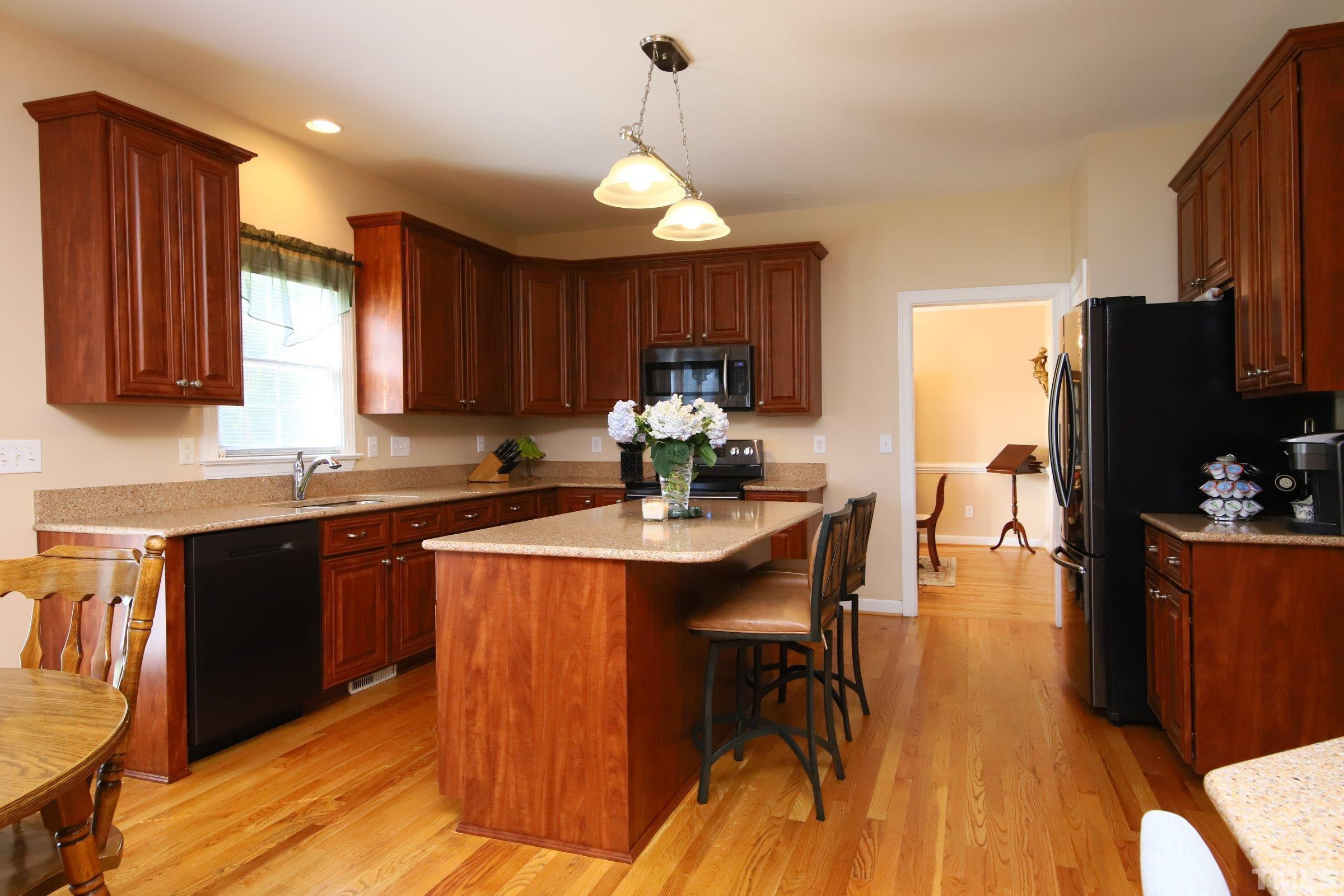 3307 Meadowrun Drive Durham, NC 27707 - Photo 19 of 29 a kitchen with stainless steel appliances granite countertop a stove top oven a refrigerator a sink dishwasher with a dining table and chairs with wooden floor