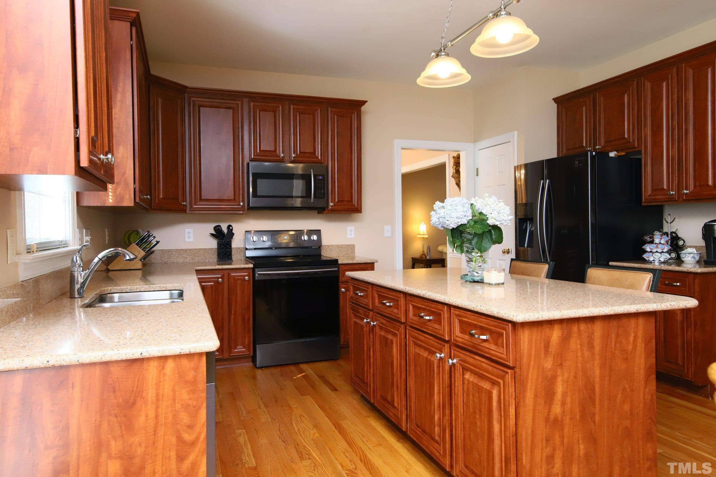 3307 Meadowrun Drive Durham, NC 27707 - Photo 20 of 29 a kitchen with stainless steel appliances granite countertop a refrigerator a stove a sink dishwasher and a microwave with wooden floor