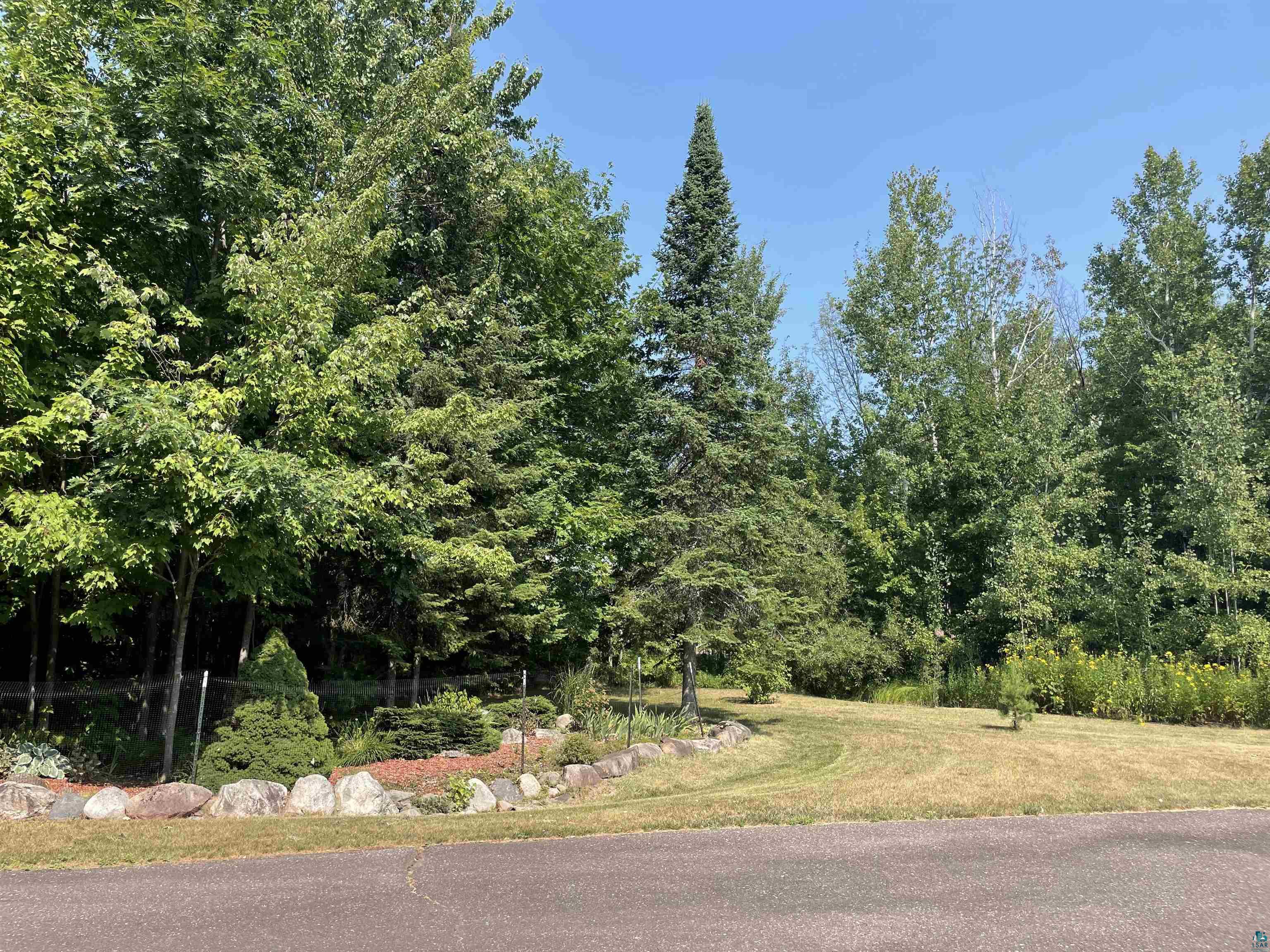 84830 Old San Road Bayfield, WI 54814 - Photo 22 of 30 Manicured lawn with mature trees and a rock-lined garden bed