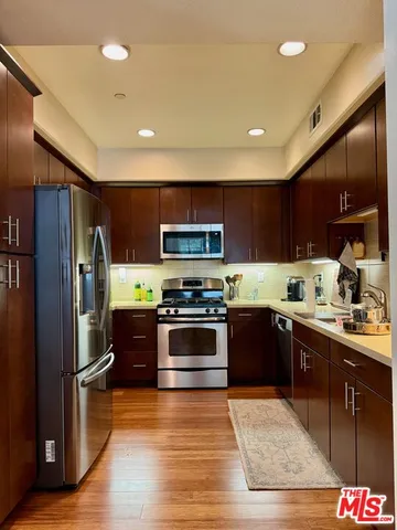 a kitchen with stainless steel appliances granite countertop a refrigerator a sink and a stove