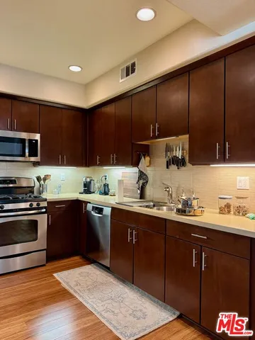a kitchen with stainless steel appliances granite countertop wooden cabinets a stove top oven a sink and dishwasher