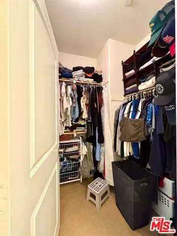 a view of walk in closet with clothes and shoes