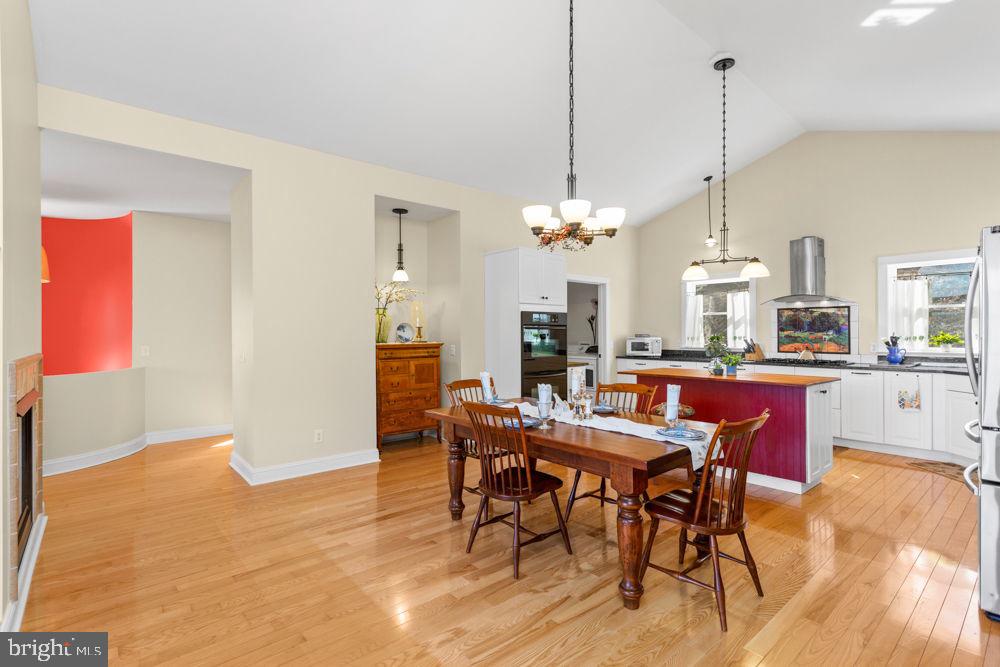 9586 Brunk Spring Lane Broadway, VA 22815 - Photo 57 of 57 a view of a dining room and livingroom with furniture wooden floor a rug a chandelier and a view of kitchen