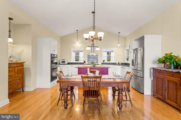 a view of a dining room and livingroom with furniture wooden floor a rug a chandelier and a view of kitchen