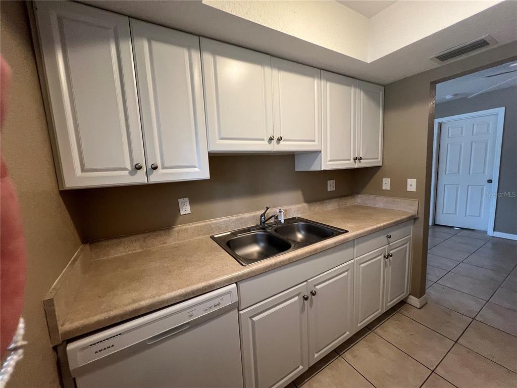 2704 2nd Street, Unit 16 Indian Rocks Beach, FL 33785 - Photo 16 of 23 a kitchen with granite countertop white cabinets and sink