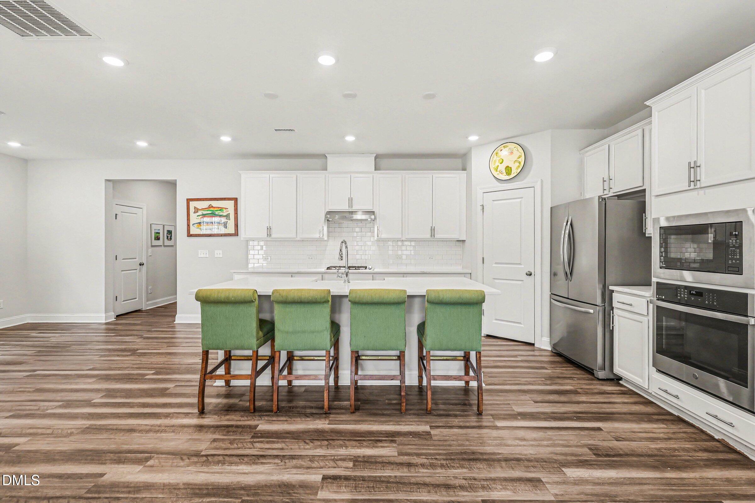 4921 Abundance Avenue Raleigh, NC 27616 - Photo 10 of 36 a kitchen with stainless steel appliances granite countertop a kitchen island hardwood floor sink and stove