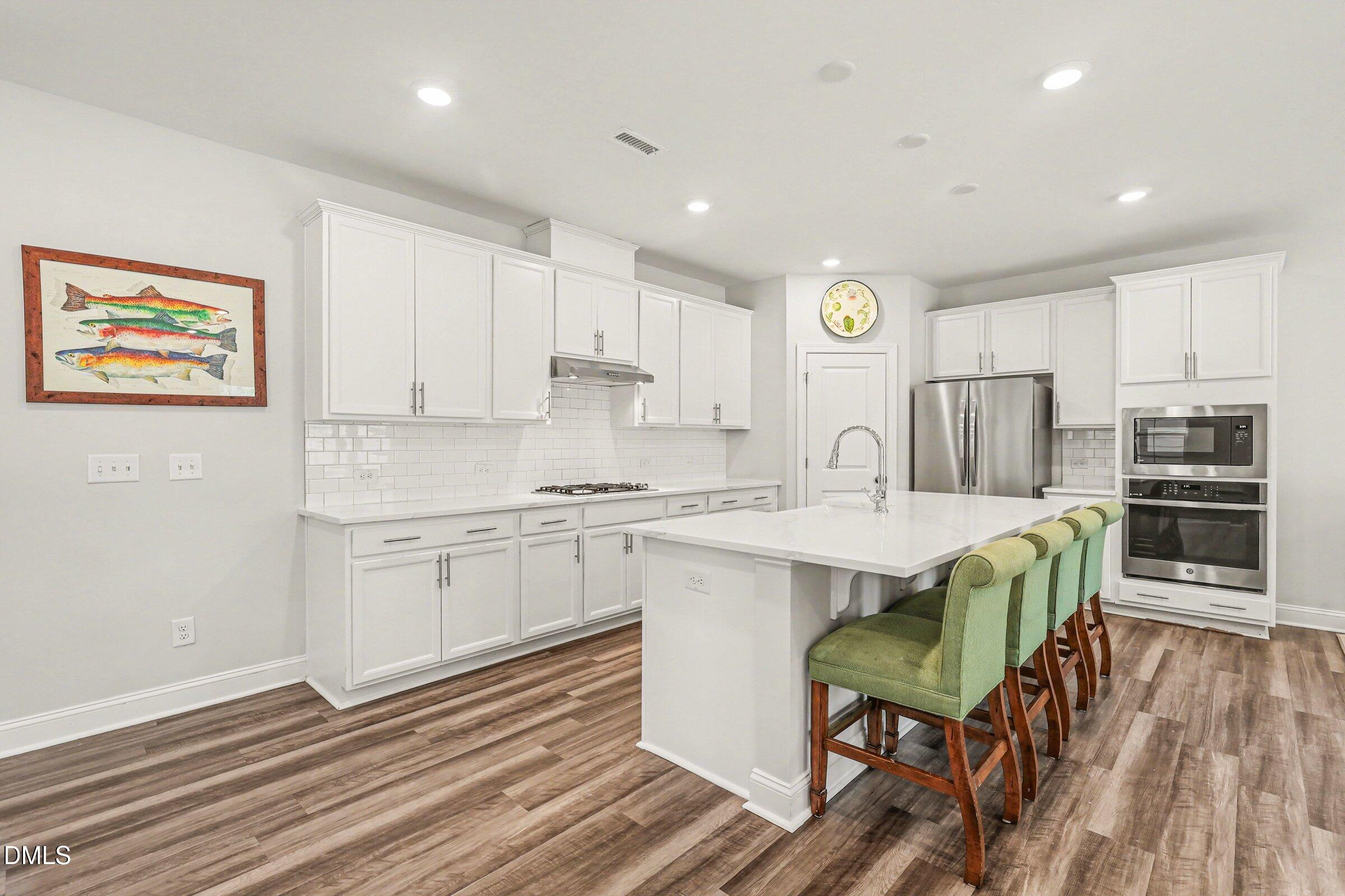 4921 Abundance Avenue Raleigh, NC 27616 - Photo 12 of 36 a kitchen with kitchen island stainless steel appliances a stove a sink and a refrigerator